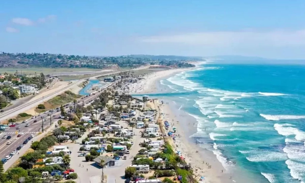 Aerial panoramic view of the beach, campground, and Highway 101 in Cardiff-by-the-Sea, California, on a sunny day.