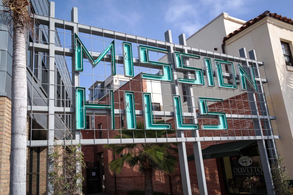 Mission Hills neighborhood sign above shops and palm trees, San Diego.