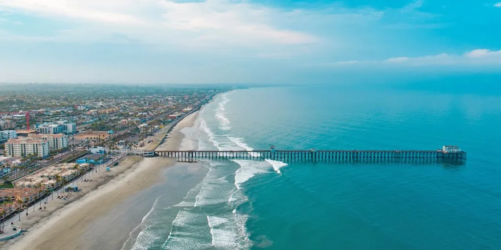Aerial view of Oceanside coastline and pier along the Pacific Ocean.