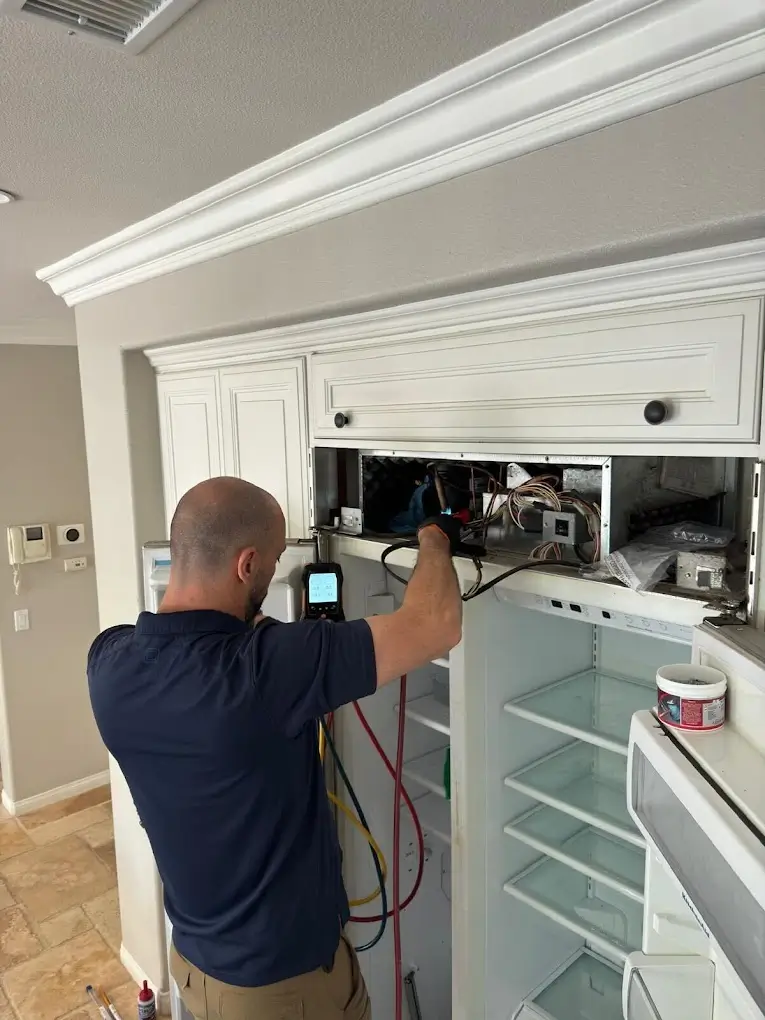 Professional freezer repair technician servicing upright freezer in modern home