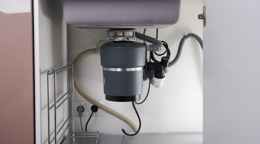 Close-up of a garbage disposal repair under a kitchen sink.