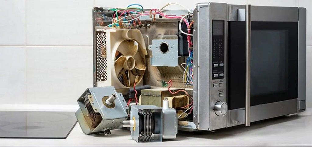 Microwave appliance opened for repair on a kitchen counter.