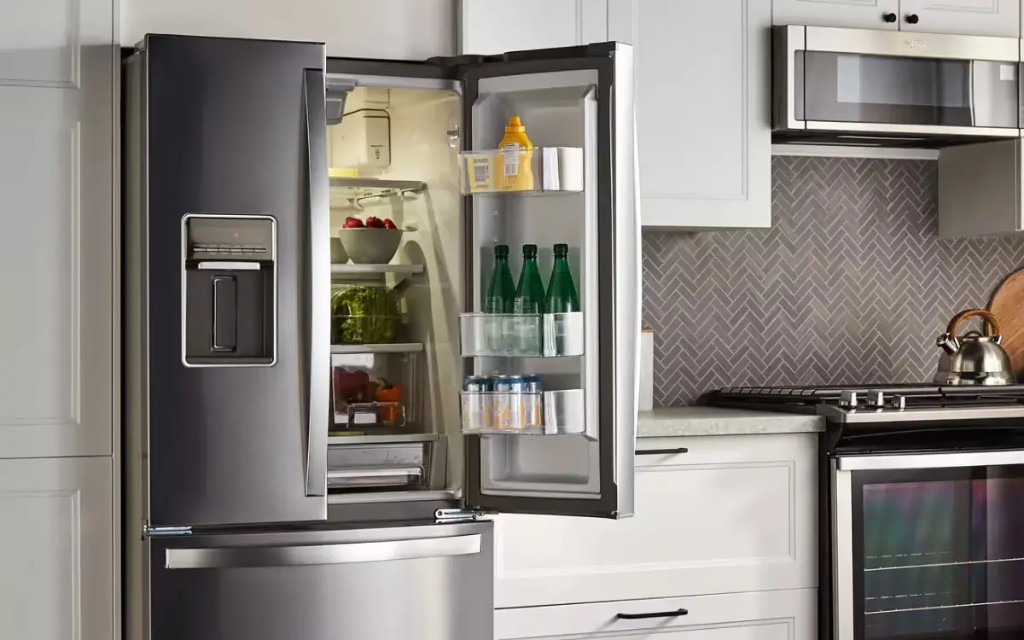 Refrigerator installation in a modern kitchen with the door open, showing the interior shelves and ice maker.