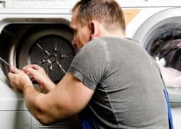 Washer repair technician examining a dryer machine.